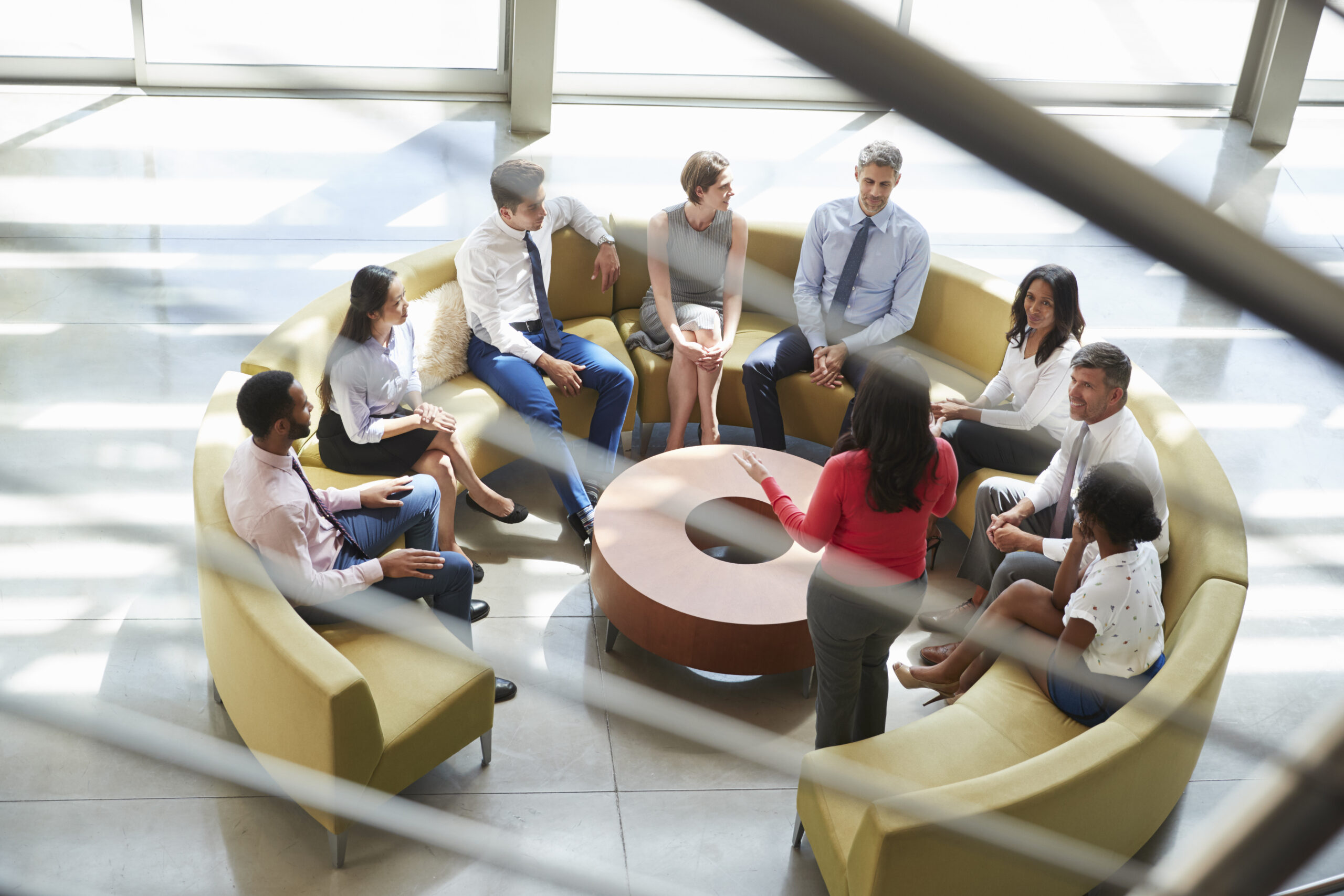 Business meeting in a lounge area, seen through stair rail